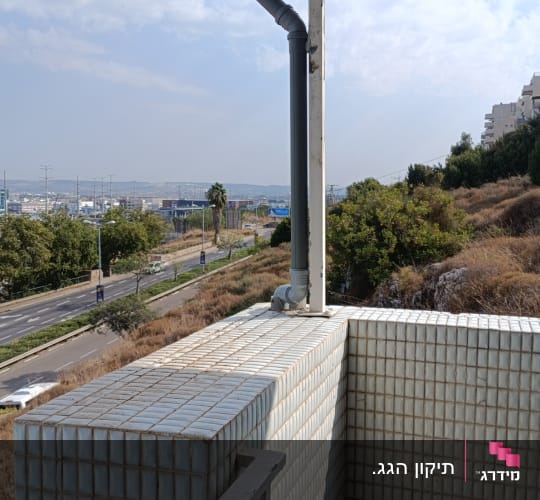מרזב אפור מחובר לגג מרפסת